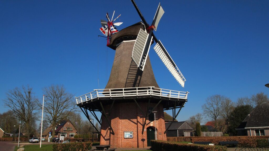 Classic Dutch windmill in a rural village under a clear blue sky on a sunny day.