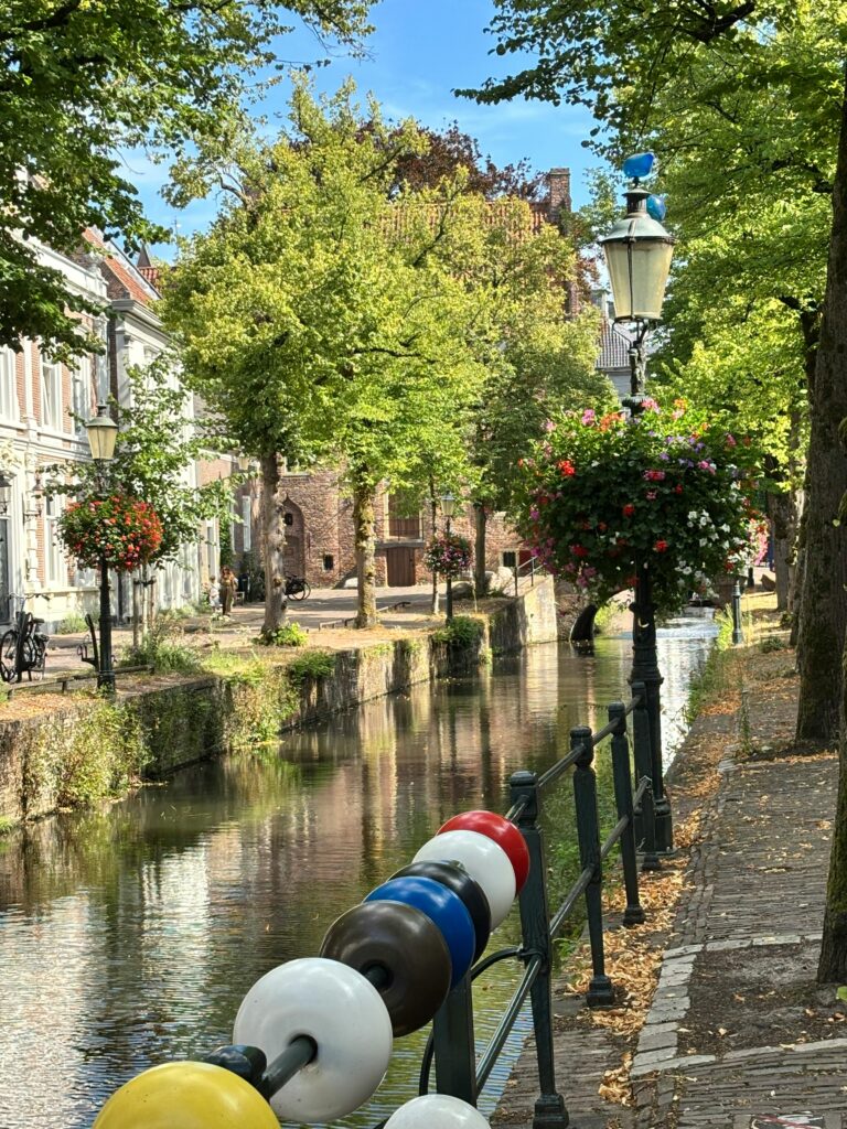 Tranquil view of a summer canal lined with greenery and historic architecture in Amersfoort, Utrecht.