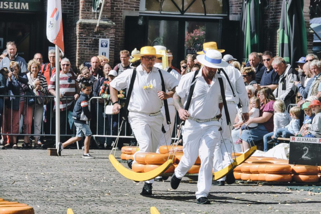 Cheese carriers in traditional attire at a vibrant festival in Alkmaar, Netherlands.