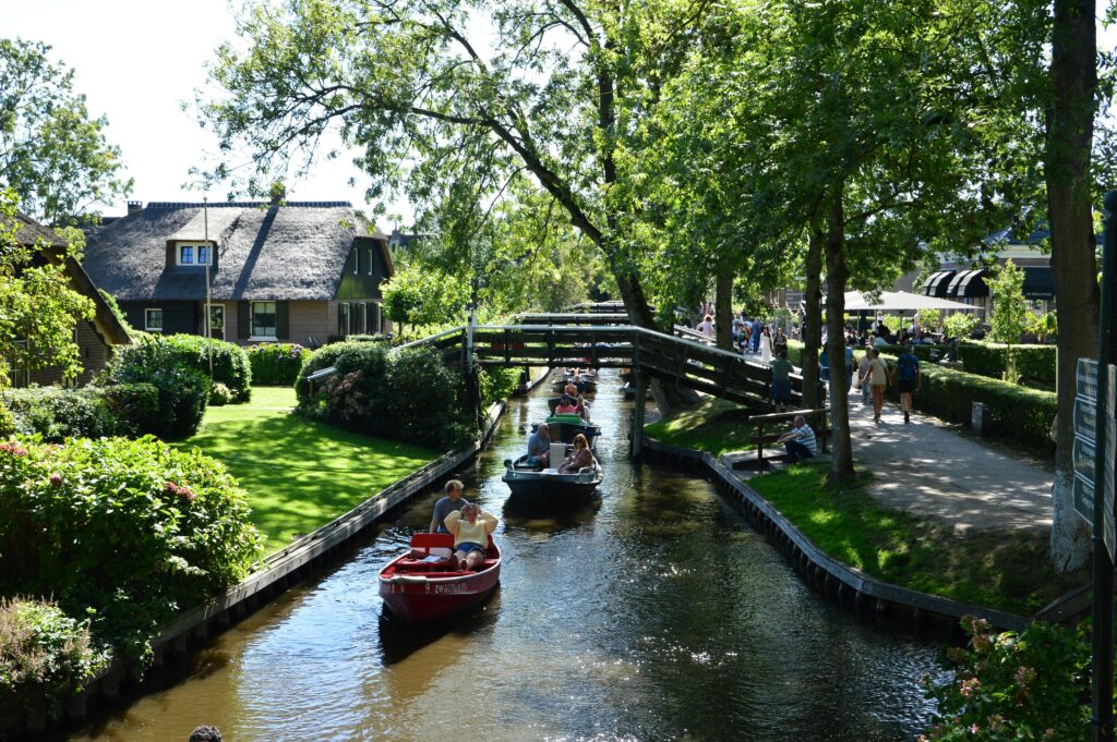 Boats glide through the picturesque canals of Giethoorn, Netherlands, under lush greenery.