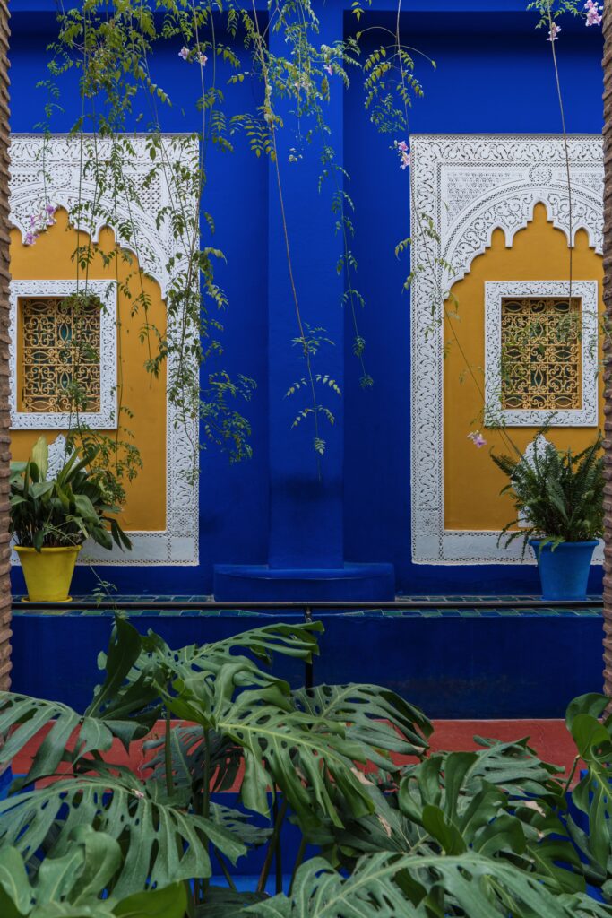 Explore the vibrant blue and yellow Moroccan architectural designs surrounded by lush greenery.