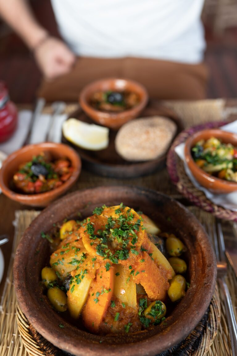 Delicious Moroccan tagine with vegetables, garnished with herbs, served in a clay pot.