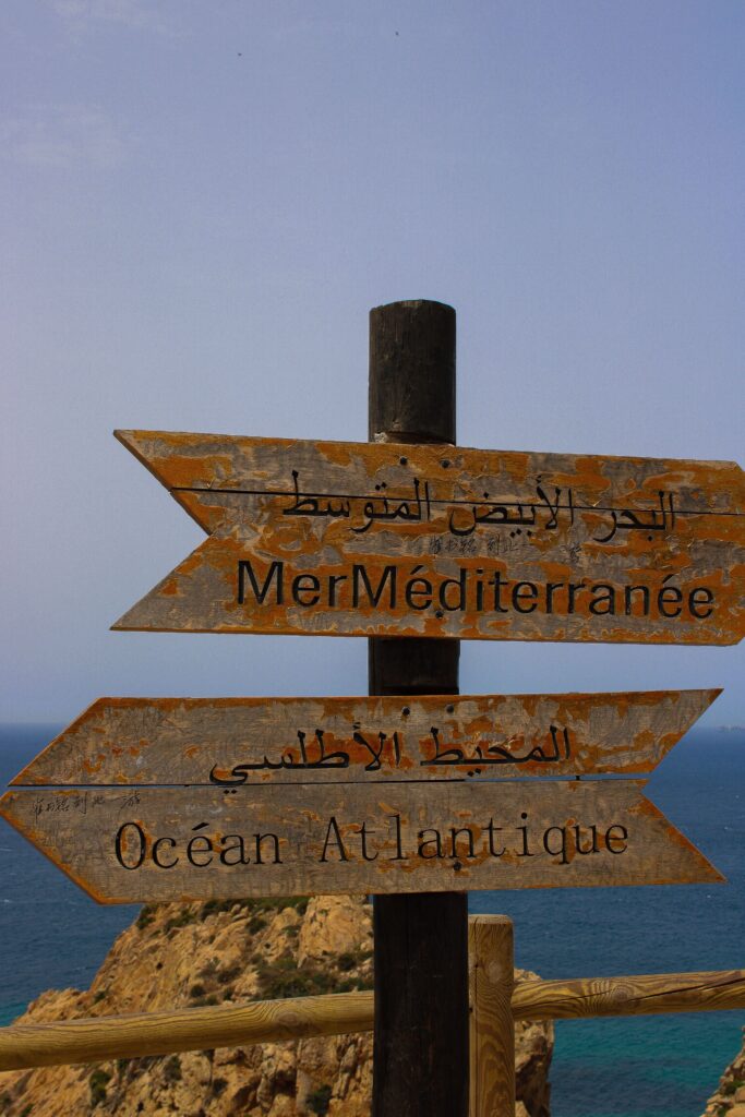 Wooden signs pointing to the Mediterranean Sea and Atlantic Ocean in Morocco.