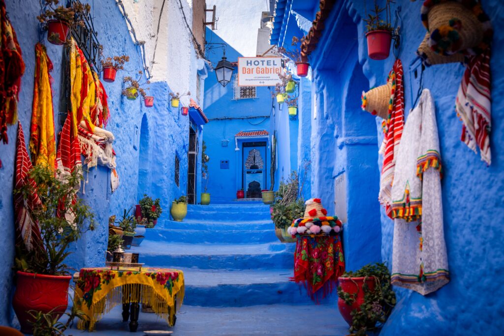 Colorful blue alleyway in the medina of Chefchaouen, Morocco with traditional textiles.